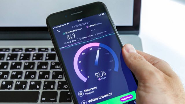 esecuzione speedtest su iPhone con laptop sullo sfondo