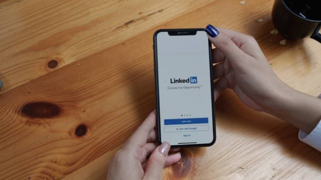 persona che ha lo smartphone con LinkedIn