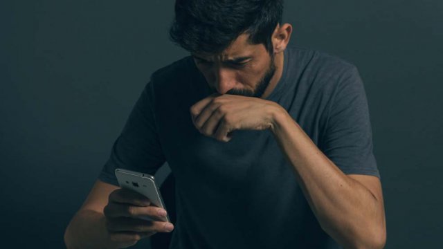 Persona triste con smartphone tra le mano