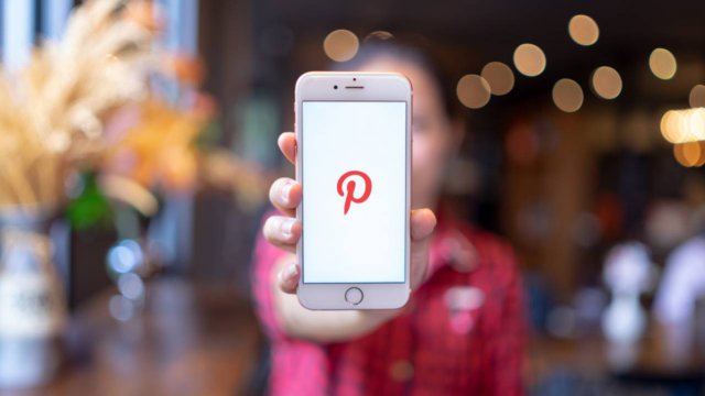 persona che mantiene uno smartphone con il logo Pinterest