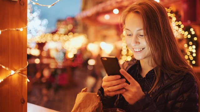 Ragazza con smartphone in una piazza natalizia