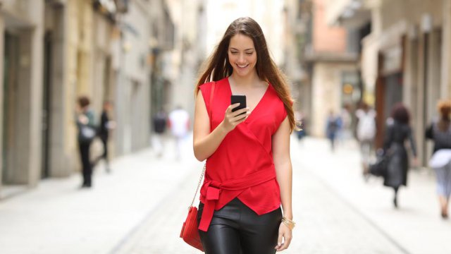Ragazza cammina in strada con smartphone in mano