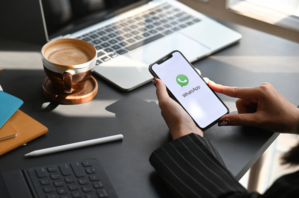 Donna-sulla-scrivania-con-in-mano-cellulare-apre-app-whatsapp