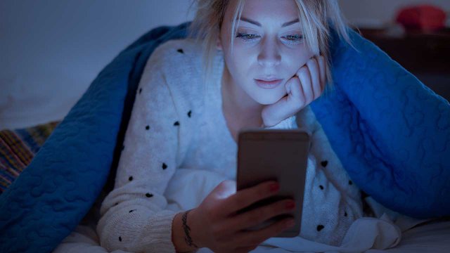 Ragazza a letto con lo smartphone