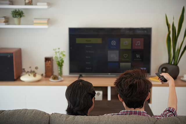 Coppia seduta sul divano guarda smart TV