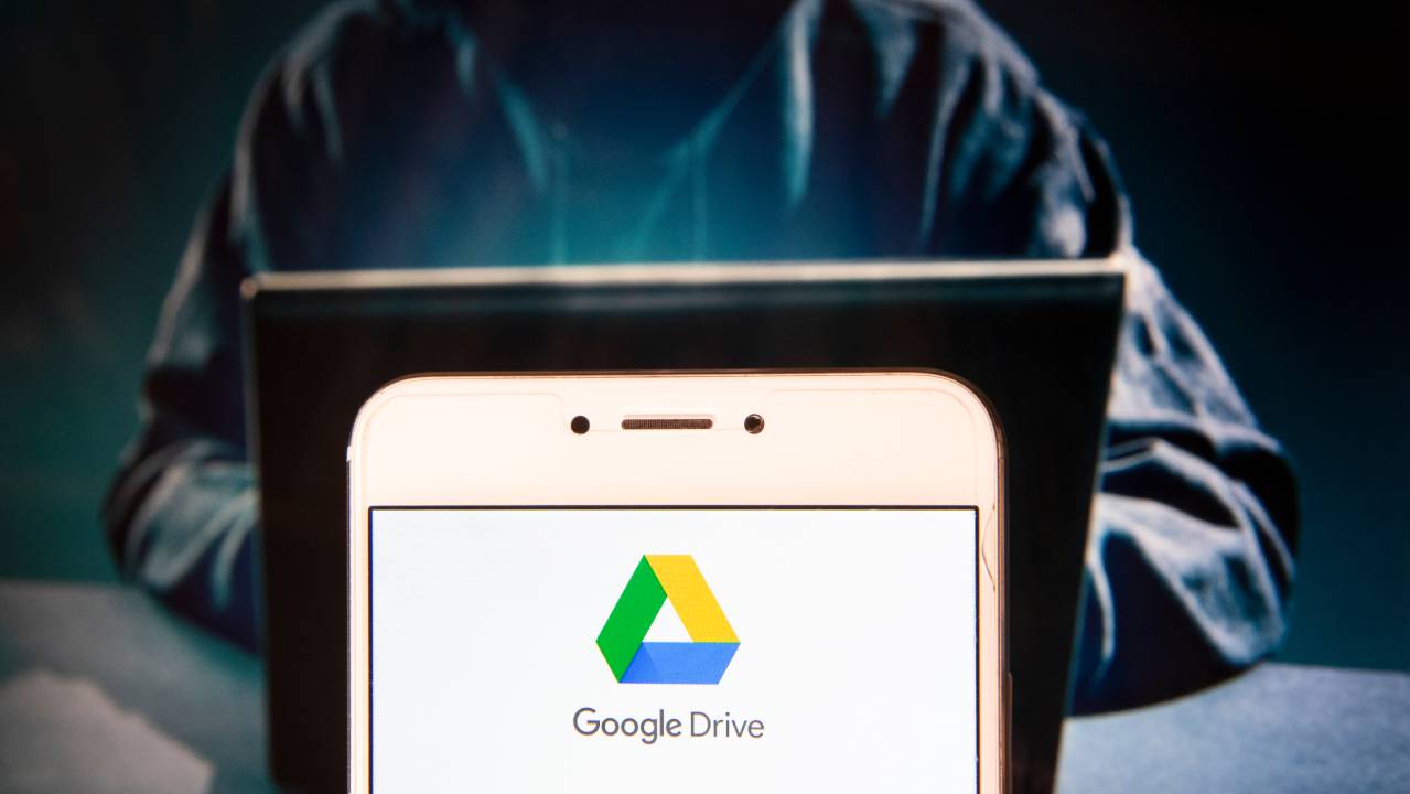 app google drive su smartphone con figura di hacker sullo sfondo