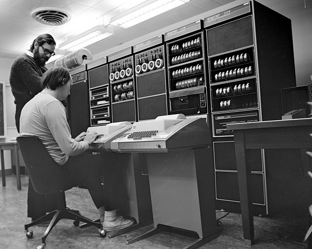 Ritchie (in piedi) al lavoro su un mainframe