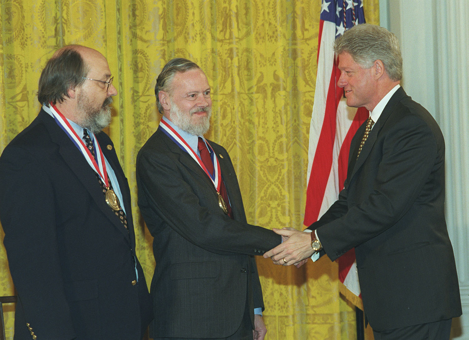 Dennis Ritchie (al centro) e Ken Thompson ritirano un'onorificenza consegnata da Bill Clinton