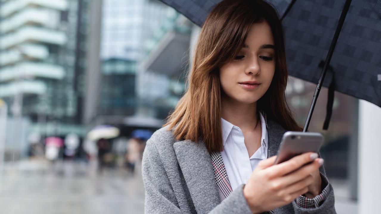 ragazza con ombrello e smartphone