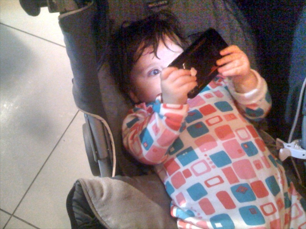 Un piccolissimo bambino digitale alle prese con uno smartphone