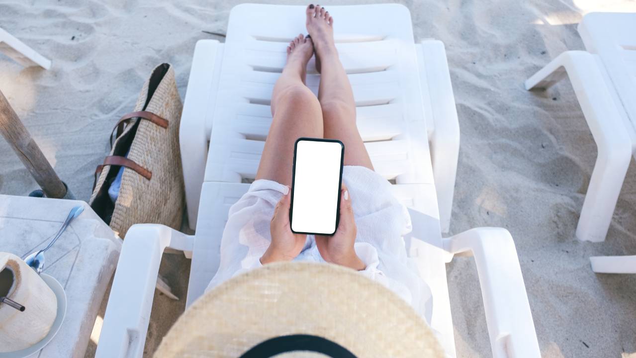 ragazza in spiaggia sdraiata con cellulare