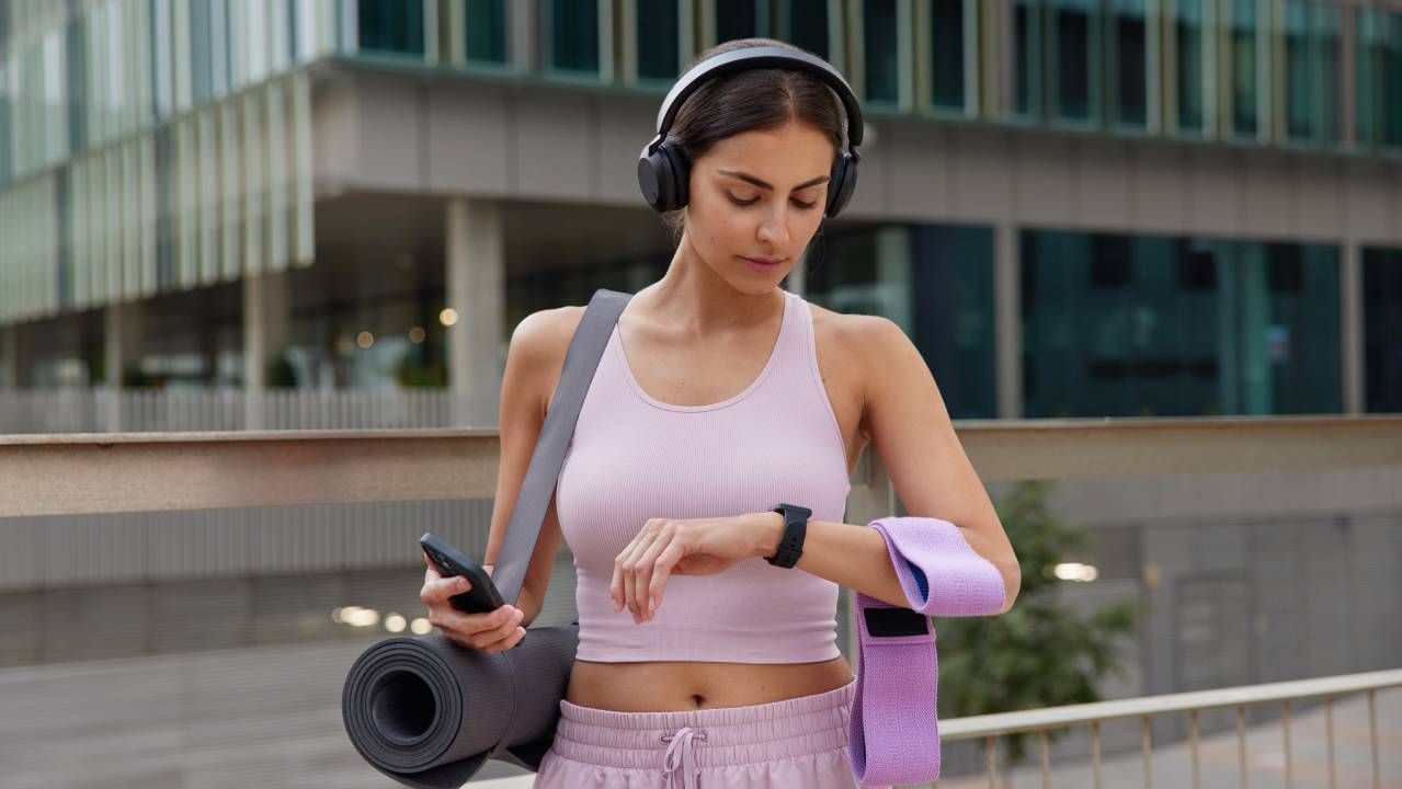 ragazza in abbigliamento fitness consulta il suo smartwatch in ambiente outdoor