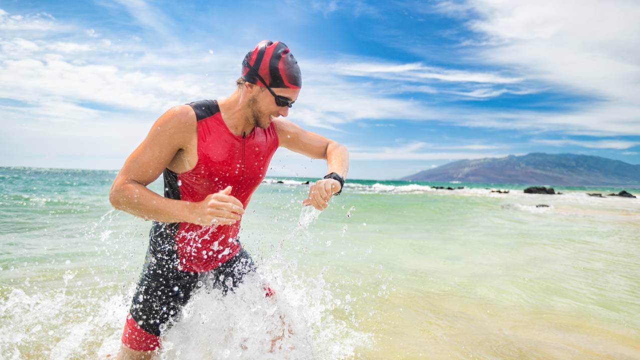 nuotatore di triathlon esce dal mare guardando il suo smartwatch