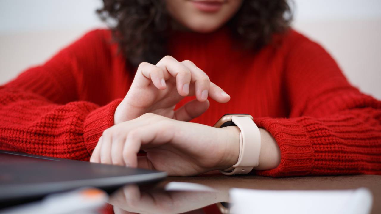 studentessa consulta il suo smartwatch seduta alla scrivania