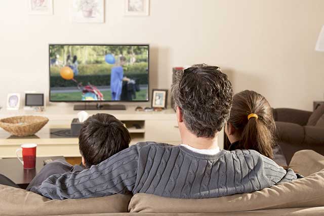 Guardare il TV in casa con la famiglia