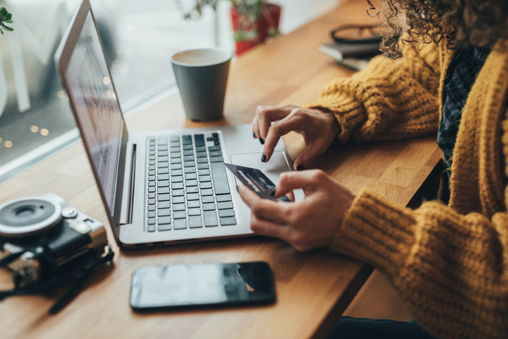 Donna in una caffetteria che fa acquisti online con un laptop