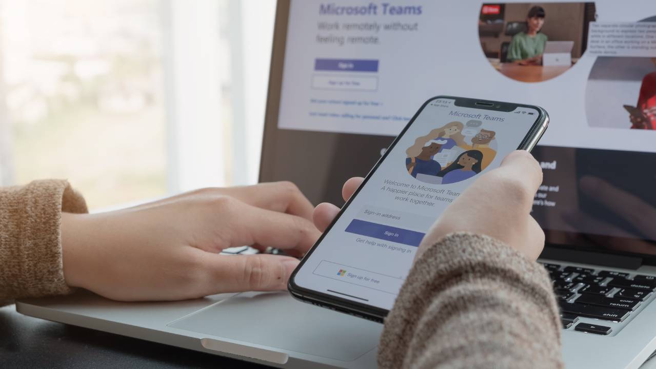 persona con pc e cellulare collegata alla home page di Microsoft Teams